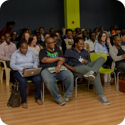 Tech support programme - social purpose Audience of people sat down at conference laughing