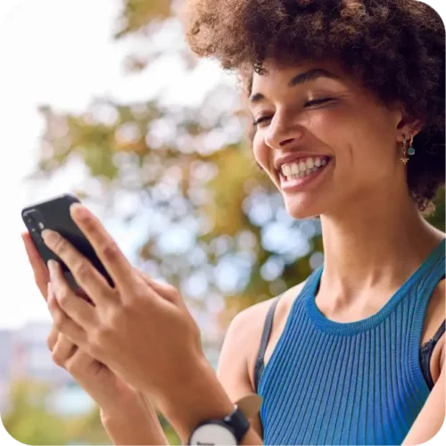 Woman smiling whilst using smartphone