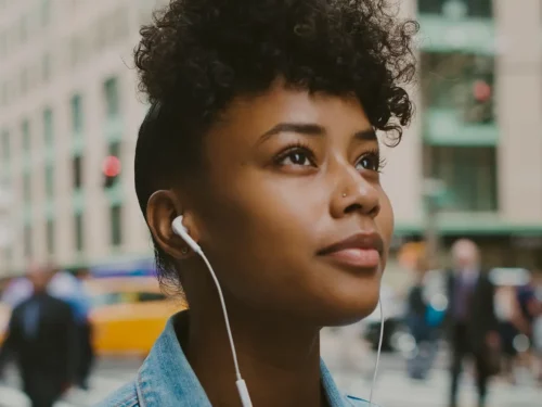 Woman walking through the street listening to her headphones