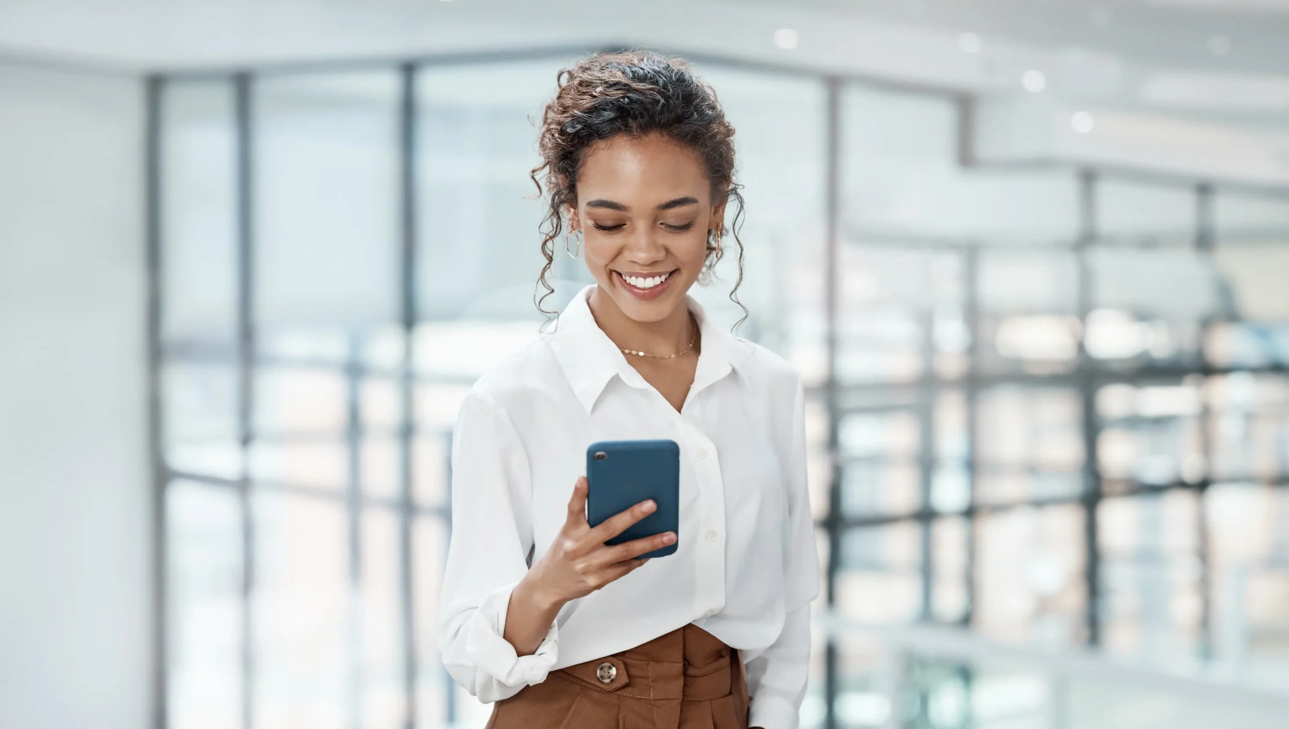 Woman in office looking at her phone and smiling