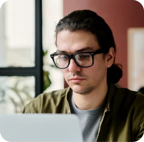 A man in glasses looking at a computer