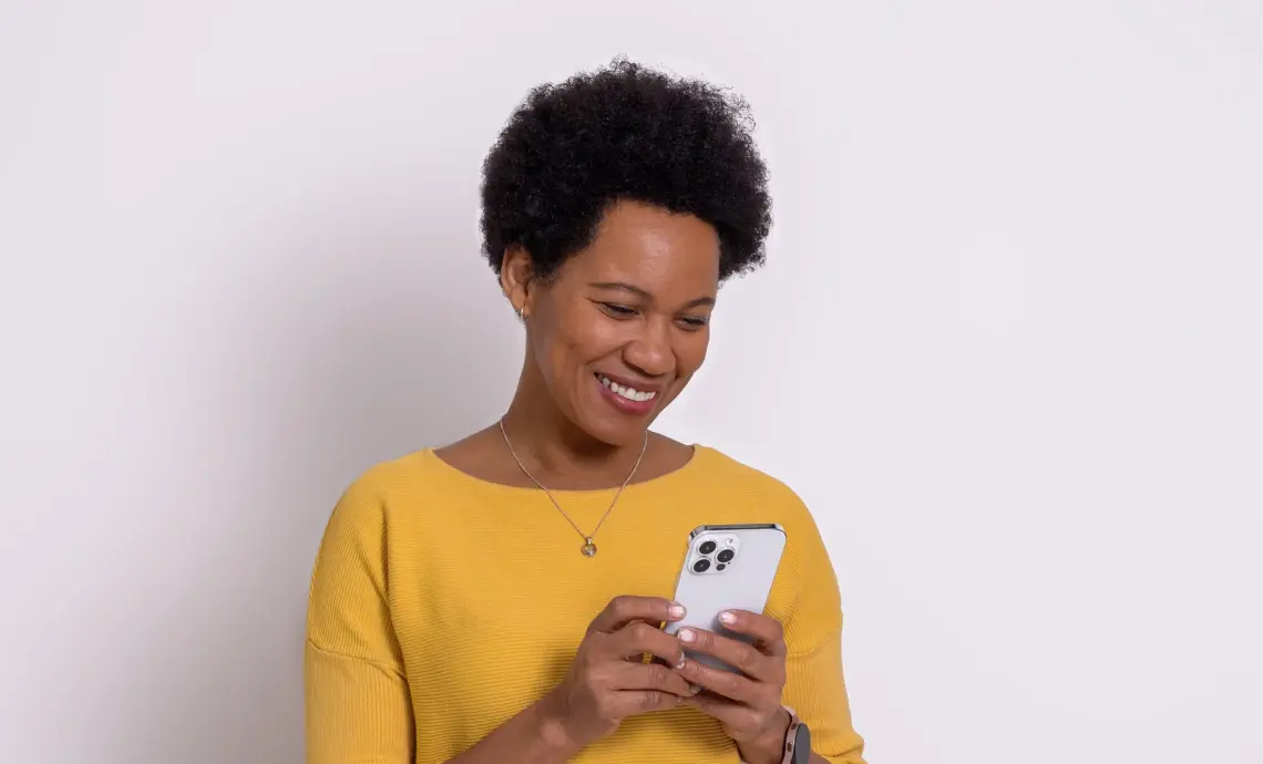 A woman smiling and using her smartphone.