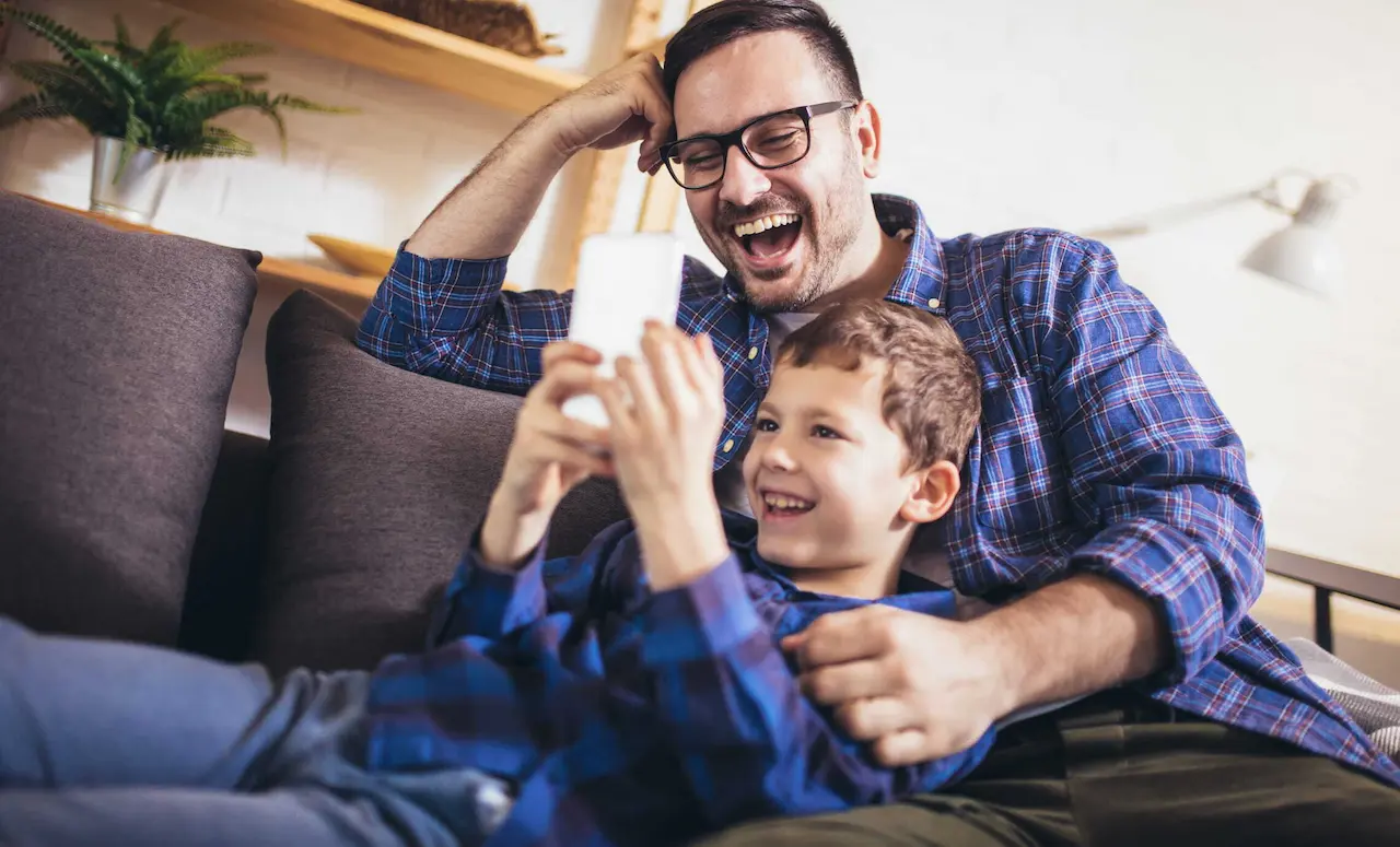 Father and son relaxing and playing games on a smartphone together