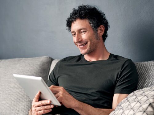 Man relaxed on sofa looking at tablet device